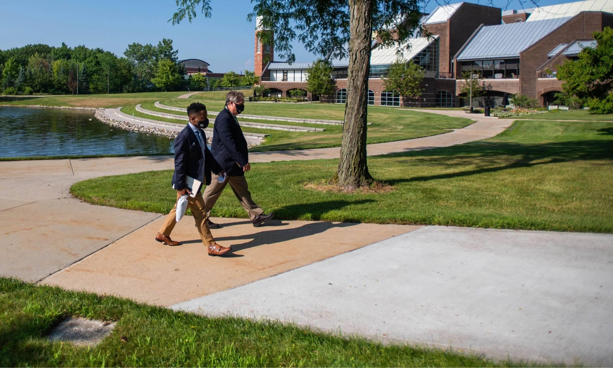 两个人走过GVSU Allendale校区的Zumberge Pond